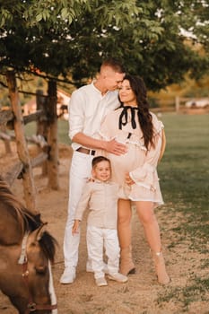 Happy family near horses at a farmer's ranch at sunset.