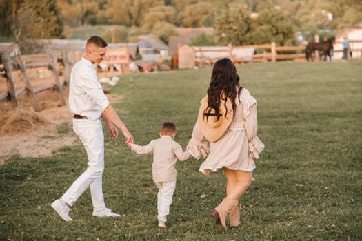 A stylish family in the countryside at sunset. A pregnant woman with her husband and son in nature.