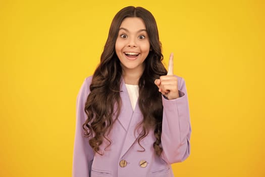 Surprised teenager girl. Funny face of young teenager pointing up with finger, isolated on yellow background. Girl has great new idea