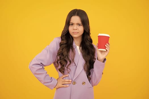 Serious teenager girl. Child girl 12, 13, 14 years old with take away cup of cappuccino coffee or tea. Teenager with takeaway mug on yellow background, morning drink beverage