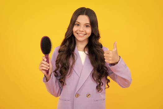 Teenager girl with long hair holding comb hairbrush for combing, beauty. Conditioner shampoo hair. Beauty kids salon. Child hairstyle. Happy face, positive and smiling emotions.