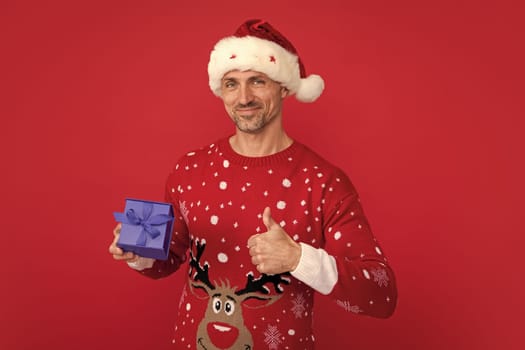 Santa with gift box. Portrait of christmas santa man on red studio background