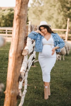 Stylish pregnant woman in a white hat in the countryside.