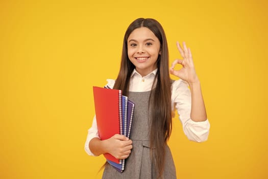 Teen girl pupil hold books, notebooks, isolated on yellow background, copy space. Back to school, teenage lifestyle, education and knowledge