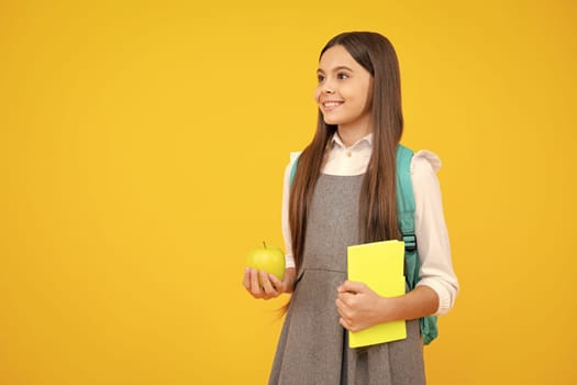 Back to school. School child, teenage student girl with bagpack hold apple and book isolated on yellow