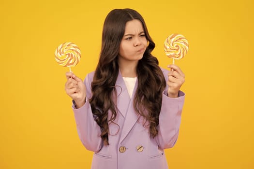 Thinking teenager girl, thoughtful emotion. Teenager girl eating sugar lollypop. Candy and sweets for kids. Child eat lollipop popsicle over yellow isolated background. Yummy caramel, candy shop