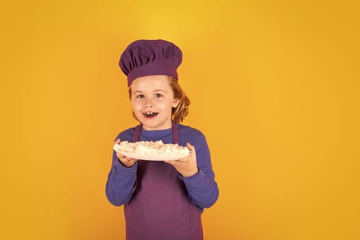 Cooking, culinary and kids. Little boy in chefs hat and apron on studio isolated background