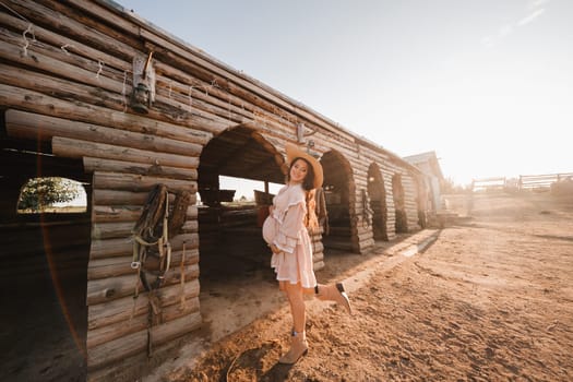 pregnant woman in a dress and hat in the countryside.