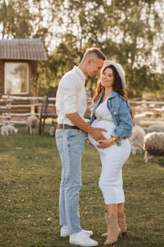 Happy man hugs his pregnant woman's belly at sunset.