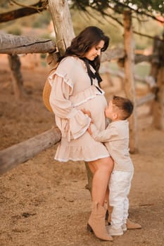 A pregnant woman with her son walks in the countryside in the summer.