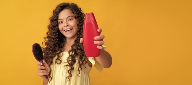 haircare and hair loss. selective focus. happy kid curly hair with comb show shampoo bottle. Kid girl hair care, horizontal poster. Banner header with copy space