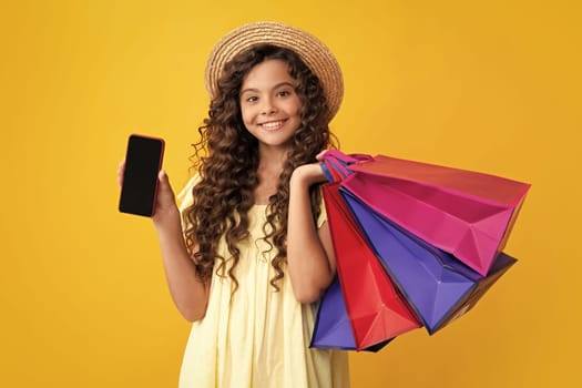 Stylish teen girl with shopping sale bags and mobile phone. Kid holding purchases. Happy teenager, positive and smiling emotions of teen girl