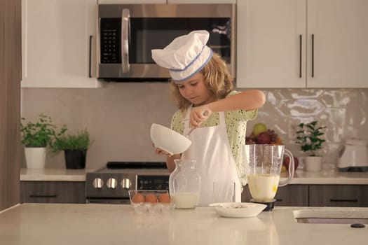 Funny kid chef cook cookery at kitchen. Chef kid boy making healthy food. Portrait of little child in chef hat