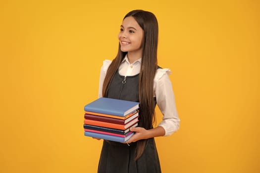 Teen girl pupil hold books, notebooks, isolated on yellow background, copy space. Back to school, teenage lifestyle, education and knowledge