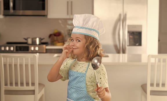 Kid chef cook wearing cooker uniform and chef hat preparing food on kitchen. Cooking, culinary and kids food concept