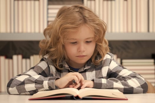 Portrait of school boy reading book in library. Kids development, learn to read. Child boy sitting in a book store, reading books