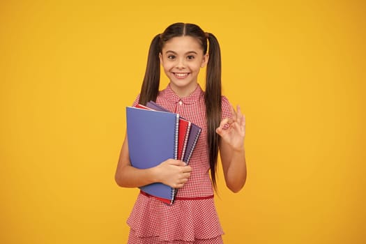 Back to school. Teenager schoolgirl with book ready to learn. School girl children on isolated yellow studio background. Happy teenager, positive and smiling emotions of teen girl