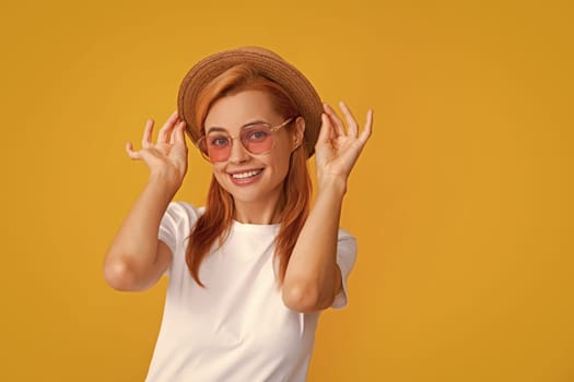 Fashion portrait pretty woman in summer straw hat over yellow background