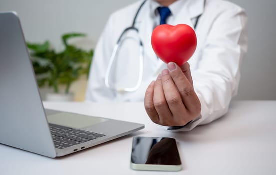 A Doctor showing a red heart at hospital office. Medical health care and doctor staff service concept.