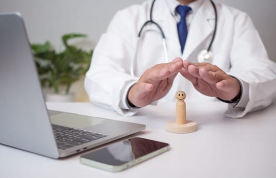 A doctor shows his hand protecting a wooden doll at a hospital. Medical health care and medical services. Insurance concept.