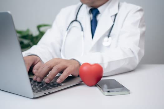A Doctor showing a red heart at hospital office. Medical health care and doctor staff service concept.