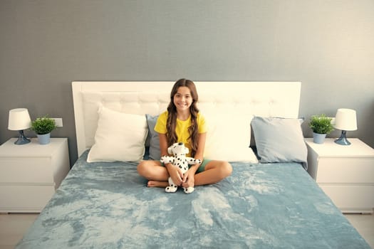Teenager child daydreaming, dreaming in bed. Kid relaxing in bedroom interior hug toy. Happy teen girl, positive and smiling emotions