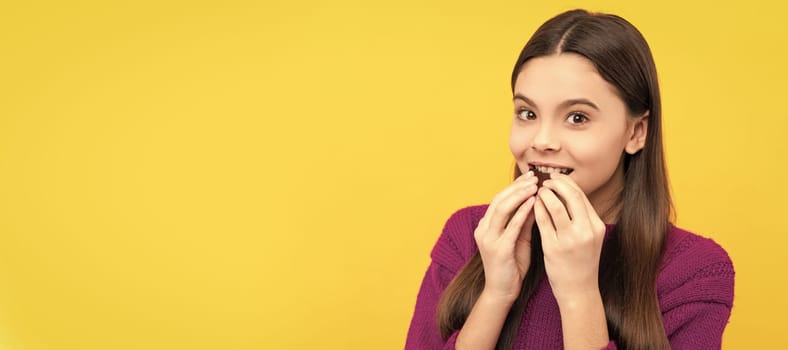 Eat it, enjoy it. Happy girl bite chocolate. Sweet tooth yellow background. Enjoy chocolate eating. Horizontal poster of isolated child face, banner header, copy space