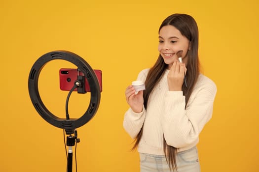 Child recording video tutorial for social media with smart phone. Influencer teenager creating new content for blog while streaming online. Beauty blog, presenting makeup cosmetics powder and brush