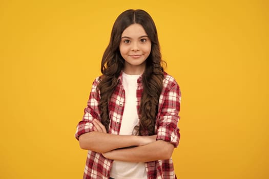 Confident child keep arms crossed, isolated on yellow background, empty space. Little caucasian teenage girl 12, 13, 14 years old hold hands crossed. Happy teenager girl