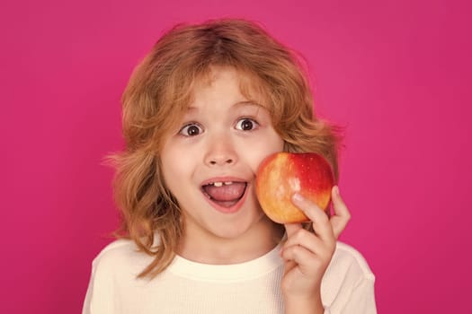 Kids face with fruits. Kid with apple in studio. Studio portrait of cute child hold apple isolated on pink background