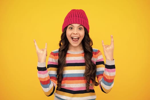 Amazed teenager. Modern teenage girl 12, 13, 14 year old wearing sweater and knitted hat on isolated yellow background. Excited teen girl