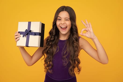 Funny face. Teenager kid with present box. Teen girl giving birthday gift. Present, greeting and gifting concept