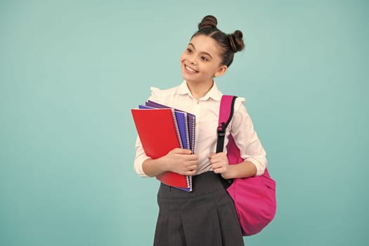 School girl hold copybook and book on yellow blue isolated studio background. School and education concept. Teenager girl in school uniform. Happy teenager, positive and smiling emotions of teen girl