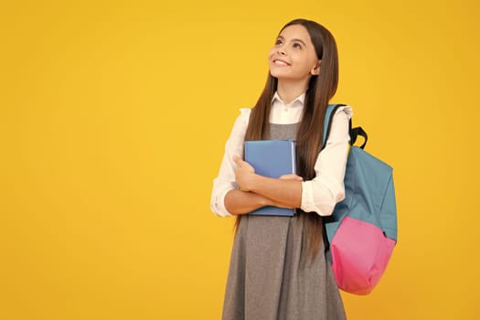 Schoolchild, teenage student girl hold book on yellow isolated studio background. School and education concept. Back to school