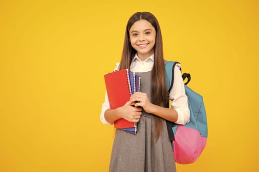 Schoolgirl, teenage student girl hold book on yellow isolated studio background. School and education concept. Back to school