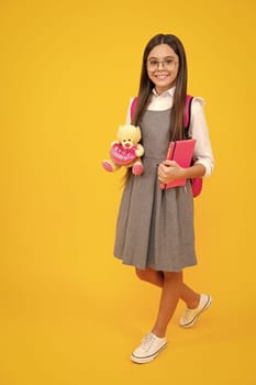 School girl hold toy. School children with favorite toys on yellow isolated background. Childhood concept