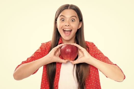 Child girl eating an apple over isolated white background. Tennager with fruit. Portrait of emotional amazed excited teen girl