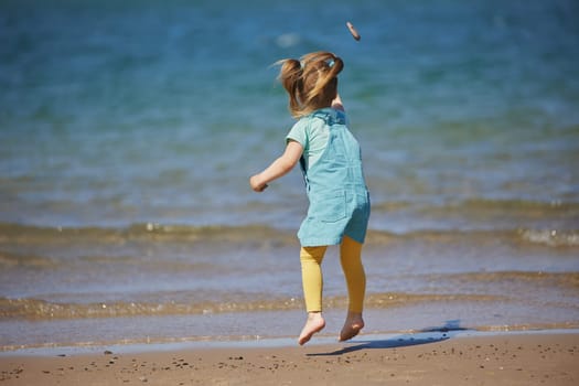 Charming child throws a stone into the sea in Denmark.