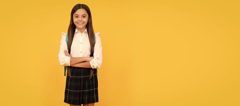 happy teen girl in school uniform full length crossed hands on yellow background, school fashion. Horizontal isolated poster of school girl student. Banner header portrait of schoolgirl copy space