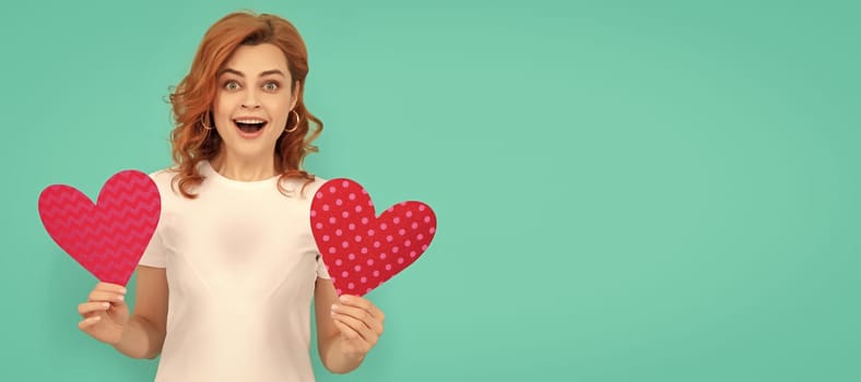 happy shocked young woman with red heart on blue background. Woman isolated face portrait, banner with mock up copyspace