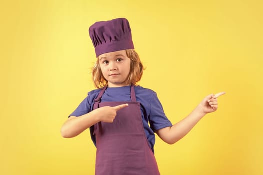 Cooking, culinary and kids. Little boy in chefs hat and apron on studio isolated background