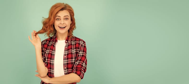 amazed redhead girl in checkered shirt on blue background. Woman isolated face portrait, banner with mock up copyspace