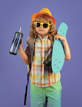 Childhood. Cute child with skateboard and water bottle on color isoalted background. Funny kid boy, stylish skater holding skateboard in studio