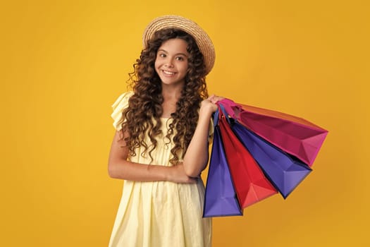 Beautiful fashion teenager child girl with shopping bags on yellow background. Shopaholic shopping and fashion. Kid with shopping sale bags. Happy teenager, positive and smiling emotions