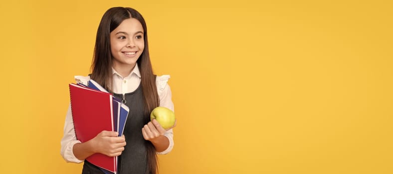 Happy girl child back to school holding apple and books yellow background, knowledge day. Banner of school girl student. Schoolgirl pupil portrait with copy space