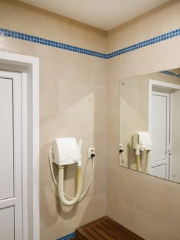 The interior of the shower room of the pool or spa center with a hairdryer and a mirror.