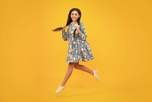 Full length little overjoyed teen girl 12, 13, 14 year old jump and fly isolated on yellow background studio