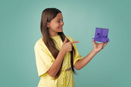 Child teen girl 12-14 years old with gift on isolated background. Birthday, holiday concept. Teenager hold present box. Happy girl face, positive and smiling emotions