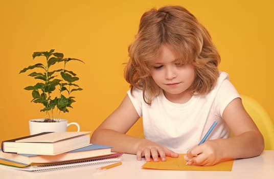 Child writing lesson. School child studying in classroom at elementary school. Kid studying on lesson on yellow isolated background. Little student, smart nerd pupil. Education and learning