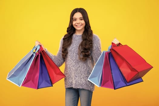 Child girl hold shopping bag enjoying sale isolated on yellow background. Portrait of teenager girl is ready to go shopping. Happy teenager, positive and smiling emotions of teen girl